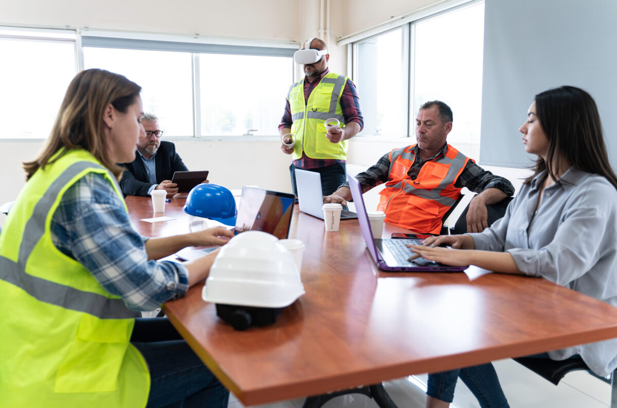 Employees participate in a virtual reality (VR) training simulation while coworkers observe during an immersive workforce training session using VR technology.